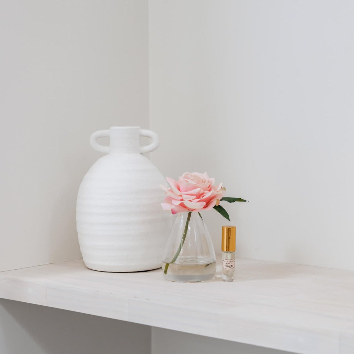 Artificial rose flower in glass vase with perfume