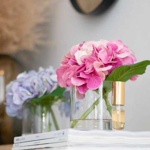 Fake purple hydrangea flower arrangement in glass vase