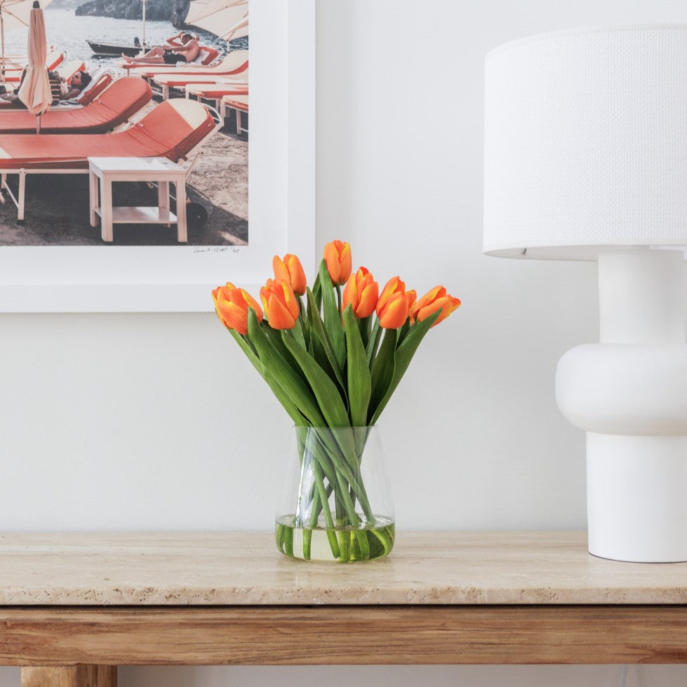 Faux tulip flower arrangemnet positioned on a side table next to a lamp