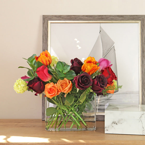Artificial rose flower arrangement in glass vase