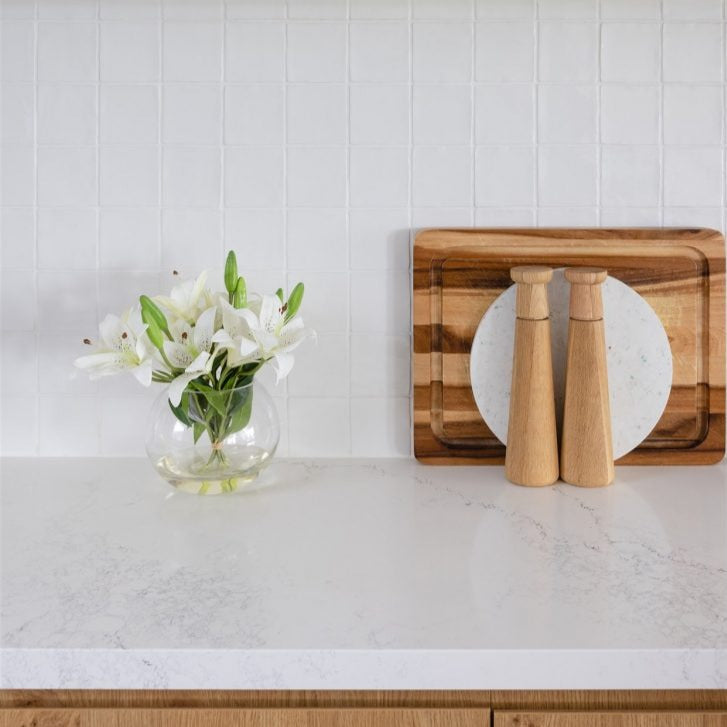 An artificial white lily arrangement being displayed on a kitchen counter top