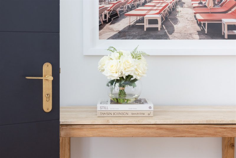 Faux white roses set in a glass vase positioned on a side table