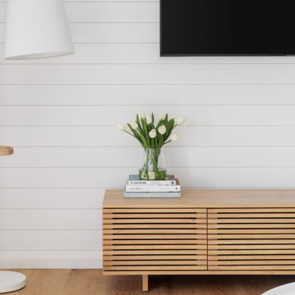 Fake white tulip arrangement positioned on a TV unit