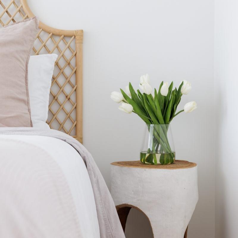 Silk tulip bouquet in glass vase on a bedside table