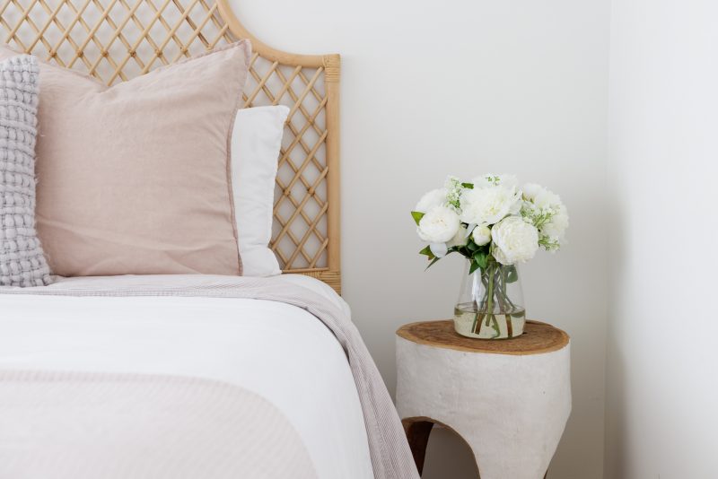 Beautiful faux arrangement of white peony flowers positioned on a bedside table